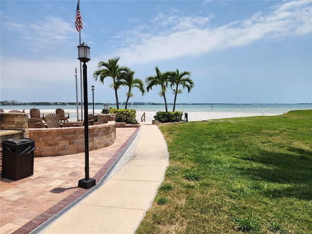 view of home's community featuring a water view, a lawn, and a beach view