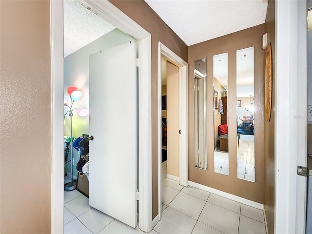 hall featuring light tile patterned floors and a textured ceiling