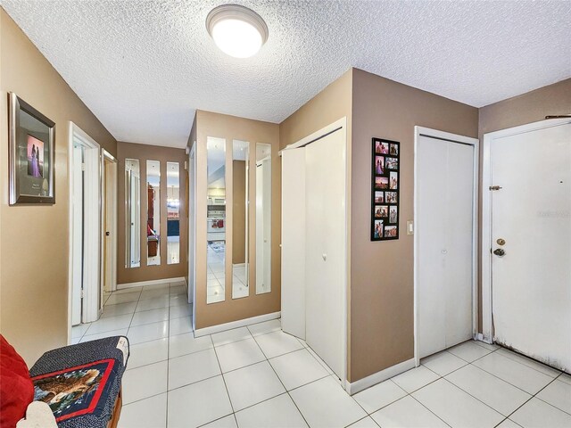 foyer entrance with a textured ceiling and light tile patterned floors