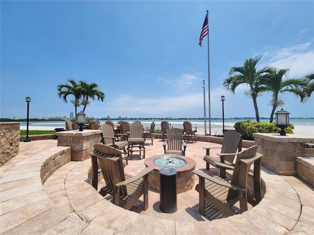 view of patio with a view of the beach, a water view, and an outdoor fire pit