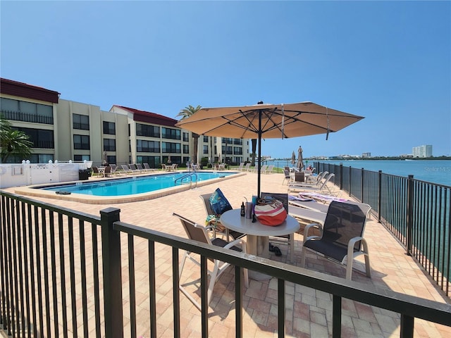 view of pool with a water view and a patio