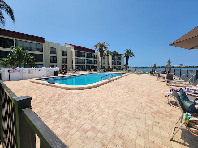 view of pool with a water view and a patio