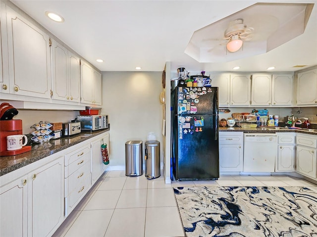 kitchen with white dishwasher, white cabinetry, light tile patterned floors, and black fridge