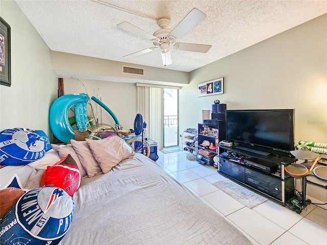 bedroom featuring ceiling fan, light tile patterned floors, and a textured ceiling