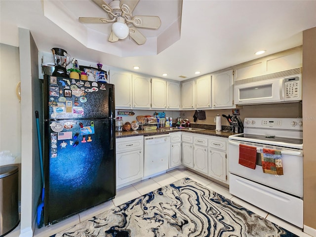 kitchen with light tile patterned floors, a tray ceiling, white appliances, and white cabinetry