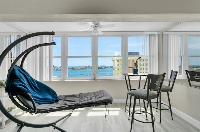 sunroom / solarium with ceiling fan and a water view