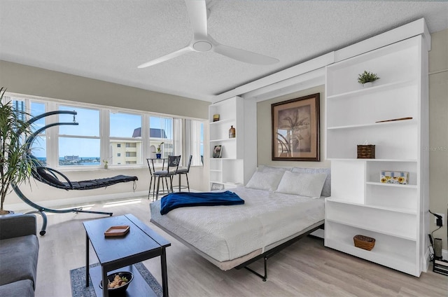 bedroom with light hardwood / wood-style flooring, ceiling fan, and a textured ceiling