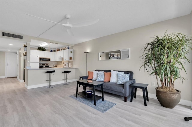 living room featuring sink, light hardwood / wood-style flooring, and ceiling fan