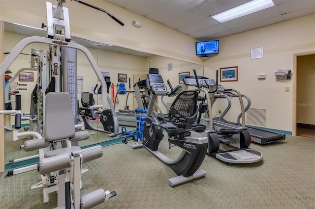 exercise room featuring carpet and a paneled ceiling