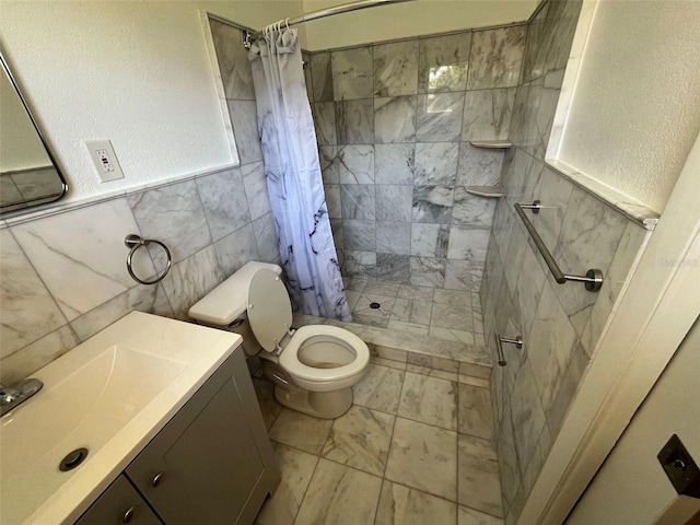 bathroom with tile flooring, tile walls, curtained shower, toilet, and vanity