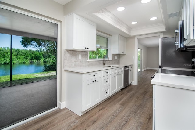 kitchen with stainless steel appliances, tasteful backsplash, hardwood / wood-style flooring, white cabinets, and sink