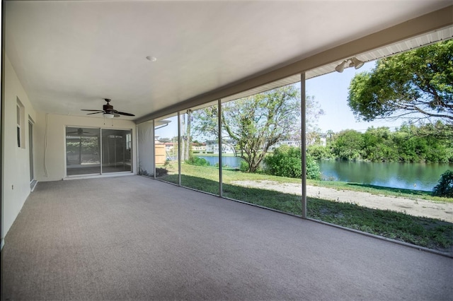 unfurnished sunroom featuring a water view, plenty of natural light, and ceiling fan