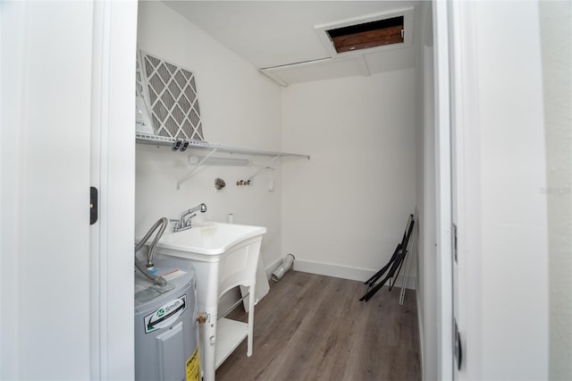 clothes washing area featuring wood-type flooring and electric water heater