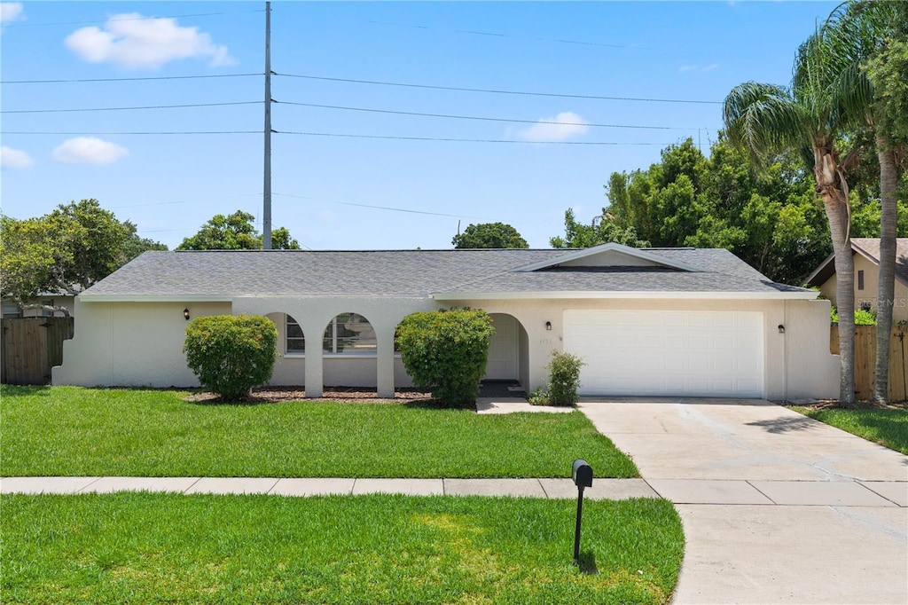 ranch-style house featuring a garage and a front lawn