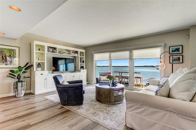 living room with light hardwood / wood-style flooring, a water view, and a textured ceiling