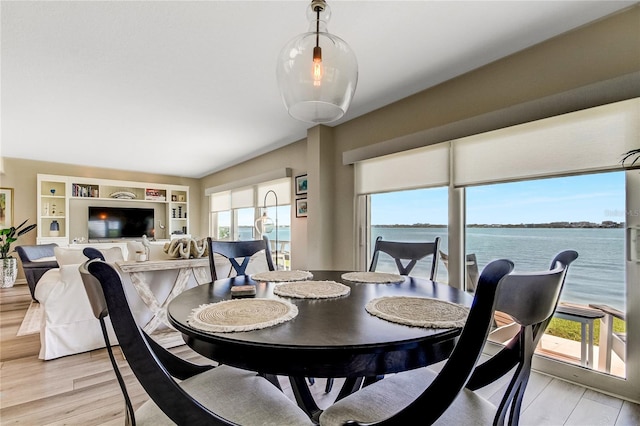 dining room with light hardwood / wood-style flooring, a water view, and built in shelves