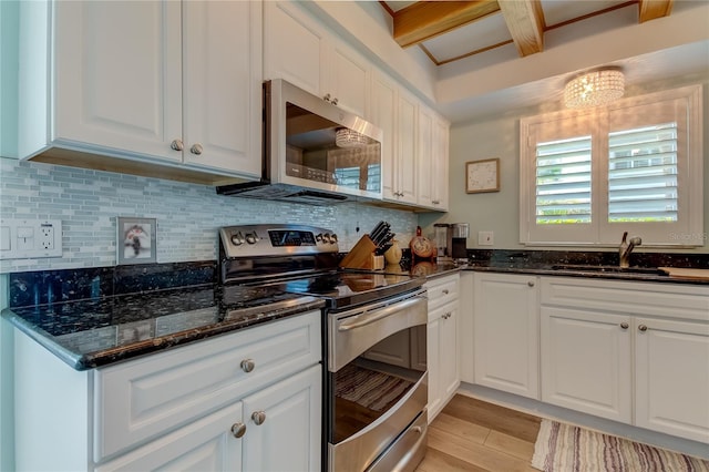 kitchen with sink, dark stone countertops, white cabinetry, and stainless steel appliances