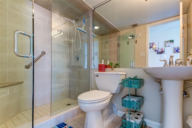 bathroom with an enclosed shower, toilet, and tile flooring