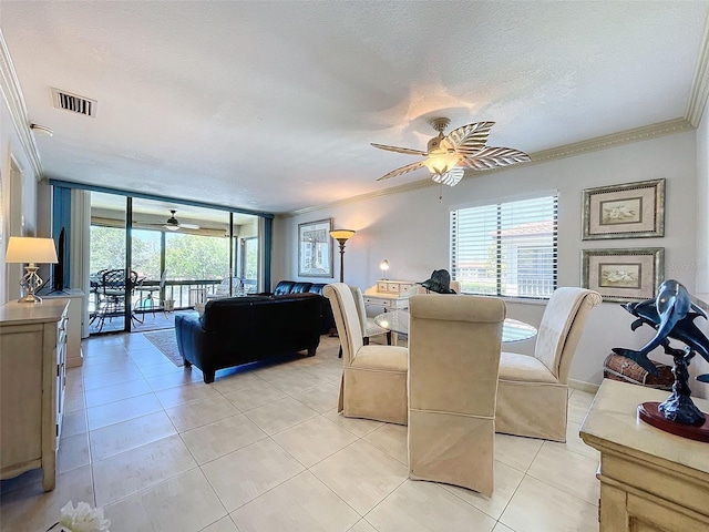 tiled dining area featuring ceiling fan, crown molding, and a textured ceiling