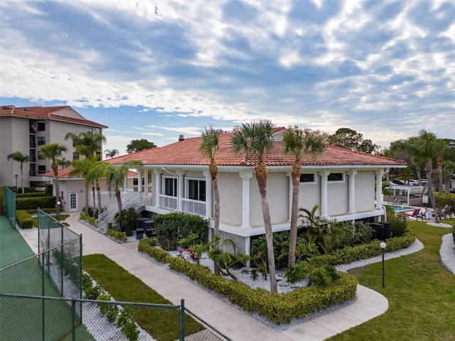 mediterranean / spanish home with a front lawn and a fenced in pool