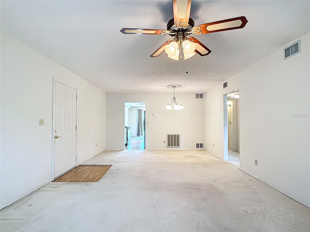 empty room featuring ceiling fan with notable chandelier, a textured ceiling, and concrete floors