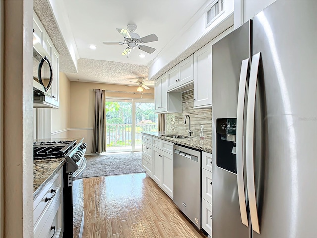 kitchen with backsplash, stainless steel appliances, white cabinets, and light wood-type flooring