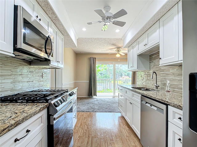 kitchen featuring white cabinets, appliances with stainless steel finishes, backsplash, and ceiling fan