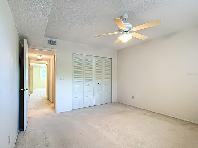 unfurnished bedroom featuring carpet flooring, a closet, ceiling fan, and a textured ceiling