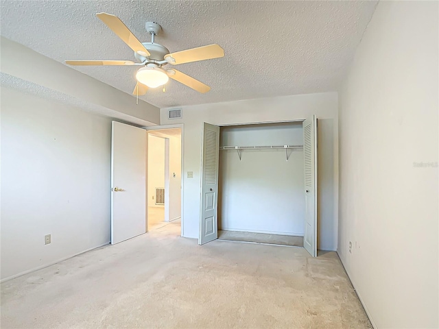 unfurnished bedroom with light colored carpet, a closet, ceiling fan, and a textured ceiling