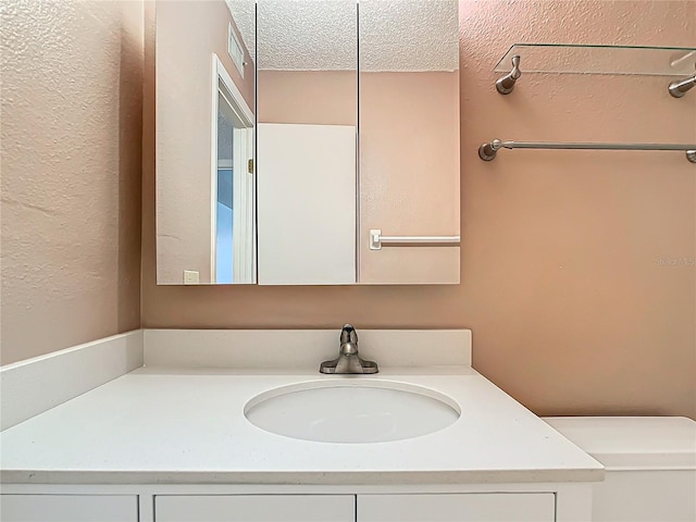 bathroom with toilet, vanity, and a textured ceiling