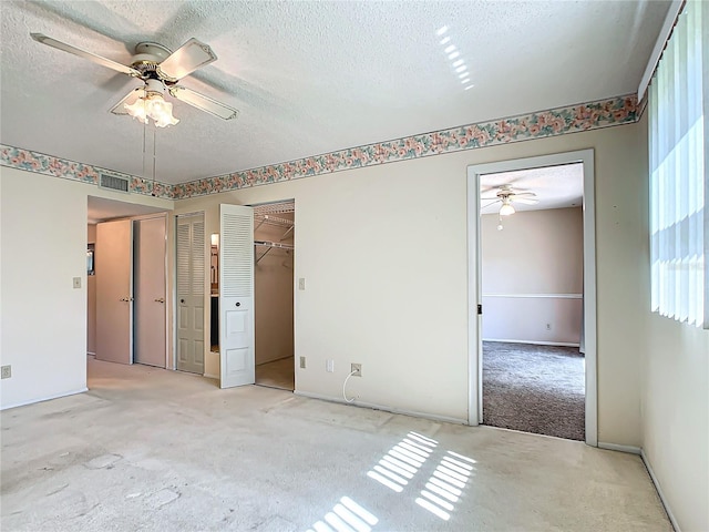 empty room with a textured ceiling, ceiling fan, and light carpet