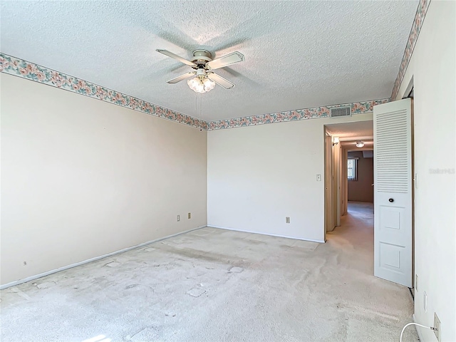 carpeted empty room with ceiling fan and a textured ceiling