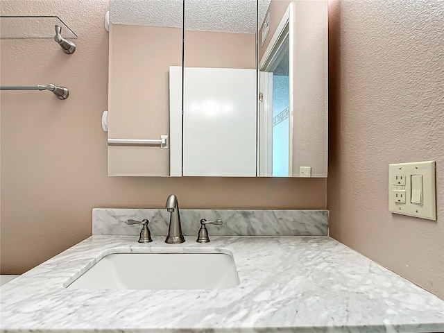 bathroom featuring a textured ceiling and large vanity