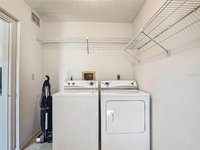 laundry room featuring a textured ceiling, hookup for an electric dryer, hookup for a washing machine, and washer and clothes dryer