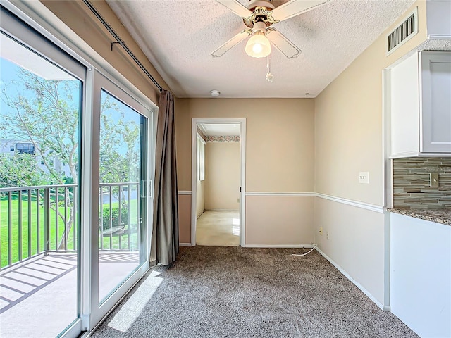 spare room with light carpet, ceiling fan, and a textured ceiling