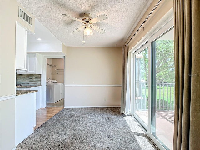 unfurnished living room with light colored carpet, a textured ceiling, ceiling fan, and washing machine and clothes dryer