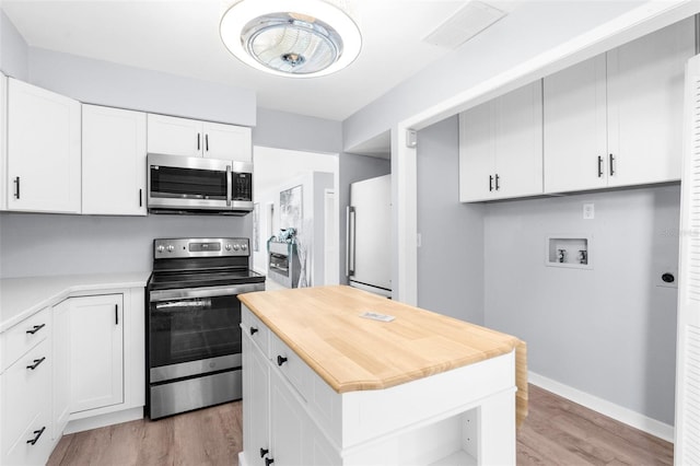 kitchen with white cabinets, a kitchen island, stainless steel appliances, and light wood-type flooring