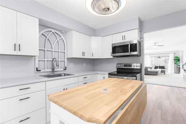 kitchen featuring appliances with stainless steel finishes, ceiling fan, white cabinets, and sink