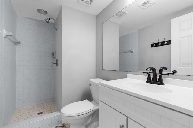 bathroom with tiled shower, vanity, and toilet