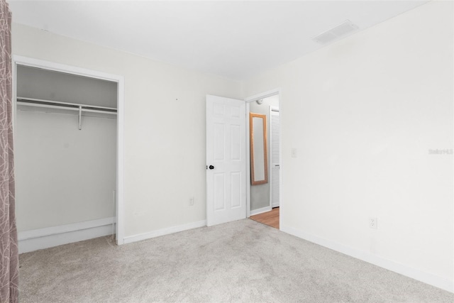 unfurnished bedroom featuring light colored carpet and a closet