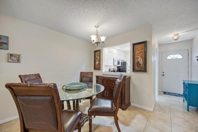 dining area with an inviting chandelier, a textured ceiling, and light tile flooring