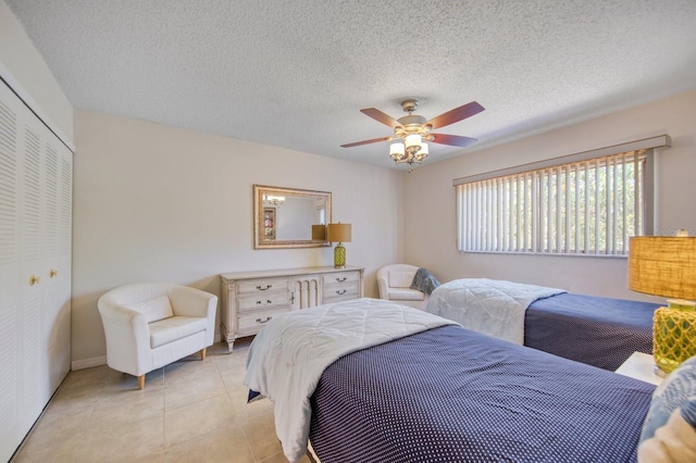 tiled bedroom with ceiling fan, a closet, and a textured ceiling