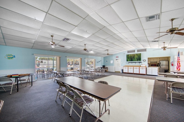 carpeted dining space featuring ceiling fan and a paneled ceiling