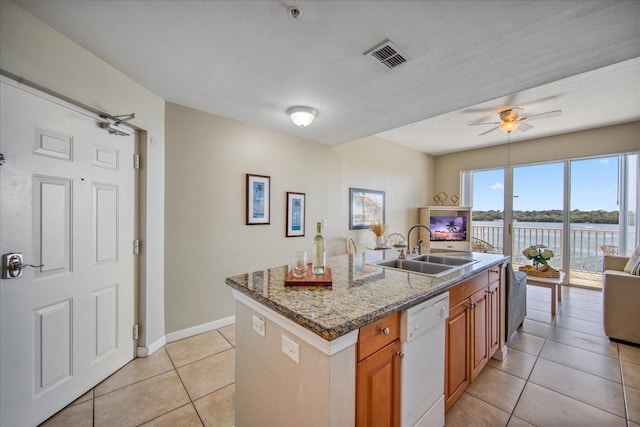 kitchen featuring dishwasher, stone counters, a center island with sink, a water view, and sink