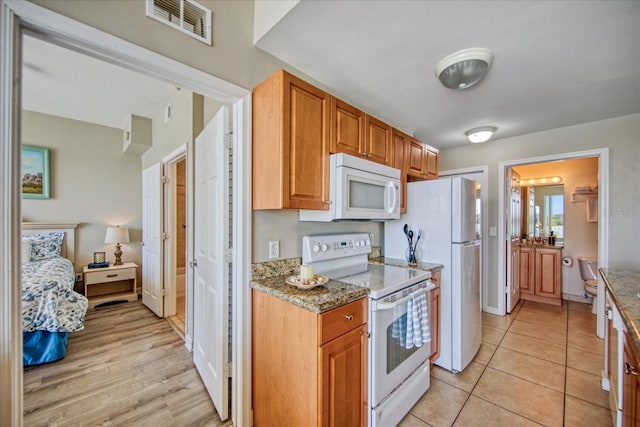 kitchen featuring white appliances, stone countertops, and light tile patterned flooring