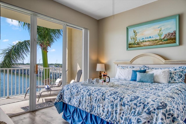 bedroom with access to exterior, wood-type flooring, and a water view