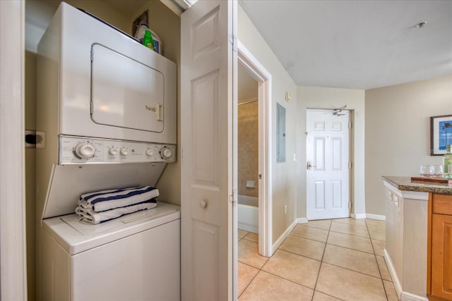 laundry area featuring electric panel, stacked washer and dryer, ceiling fan, and light tile patterned flooring