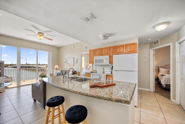 kitchen with ceiling fan, sink, light tile patterned floors, white appliances, and a water view