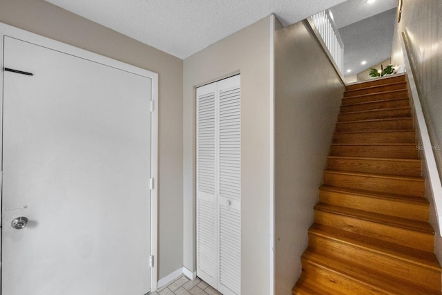 stairway featuring a textured ceiling