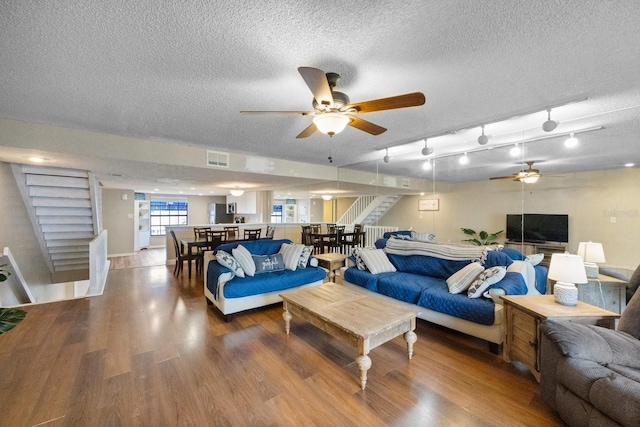 living room with rail lighting, ceiling fan, hardwood / wood-style floors, and a textured ceiling